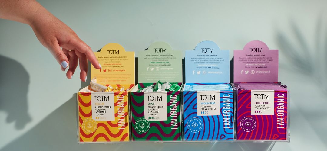 Support periods in the workplace with a free product provision. Image shows hand reaching for a tampon in one of TOTM's workplace boxes